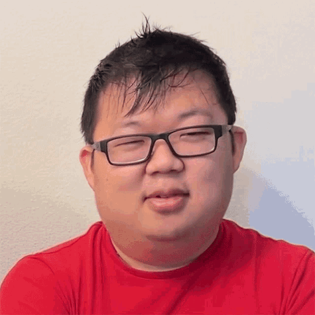 a man wearing glasses and a red shirt is making a face