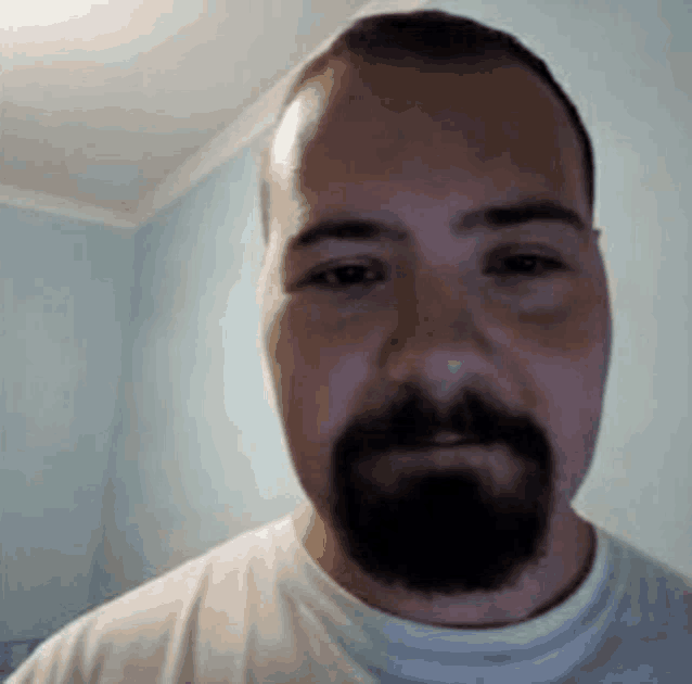 a man with a beard is looking at the camera .