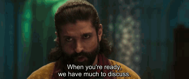 a man with a beard and long hair says when you 're ready we have much to discuss