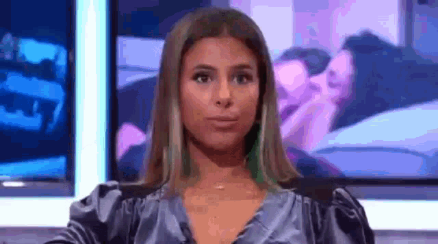 a woman is sitting in front of a television making a face .