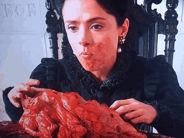 a woman with blood on her face holds a piece of meat