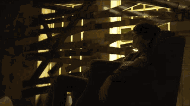 a person is sitting in a chair in front of a wooden wall