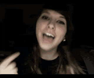 a close up of a woman making a face with her hands in the dark