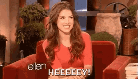 a woman is sitting in a red chair and smiling while talking to ellen degeneres .