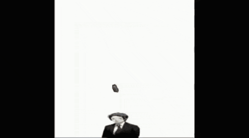 a man in a suit and hat is standing in front of a red brick with a face on it ..