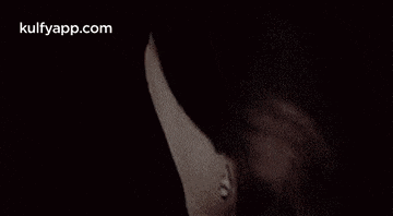 a close up of a woman 's face with her mouth open and a black background .