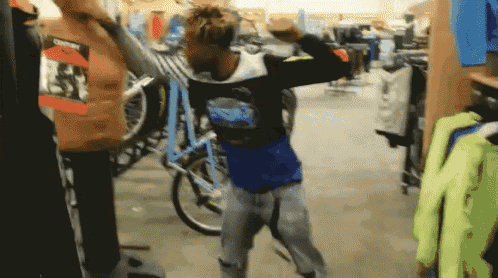 a man in a blue shirt is standing in a store with a bicycle in the background