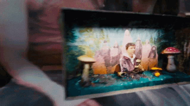 a person is holding a picture of a man sitting on a table