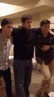 three men are standing next to each other and one of them is carrying another man on his shoulders