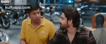 two men are sitting at a table talking to each other in a restaurant .