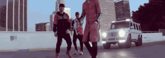 a group of men are standing in front of a mercedes