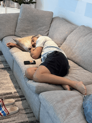 a man is sleeping on a couch with a cell phone