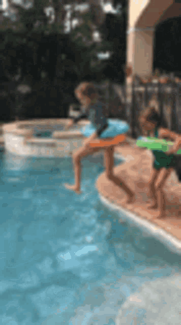 two children are playing in a swimming pool .