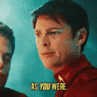 a man in a red shirt is talking to another man and says as you were