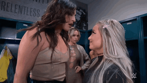 three women are standing in a locker room with a sign that says relentless