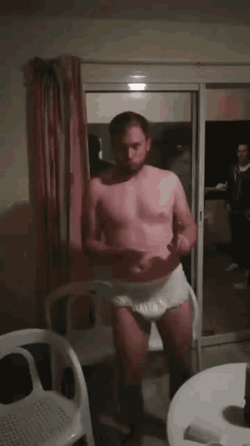 a shirtless man in white underwear is standing in front of a glass door