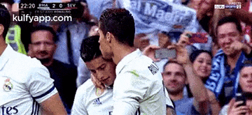 two soccer players are hugging each other in front of a crowd of people .