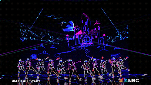 a group of people are dancing on a stage with a castle in the background and the nbc logo on the bottom
