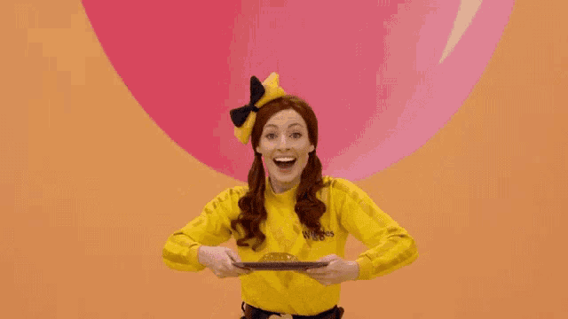 a woman in a yellow shirt is sitting in front of a pink heart .