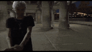 a man with white hair is standing in a dark room with graffiti on the walls