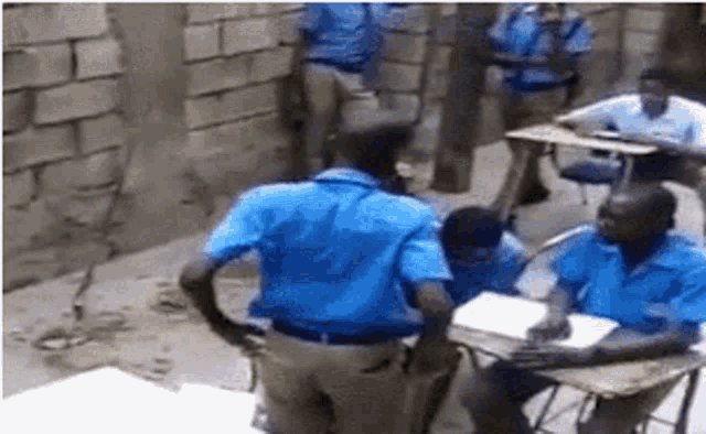 a group of people in blue uniforms are sitting at desks .