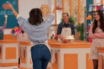 a woman in an apron is dancing in front of a sign that says cake on it