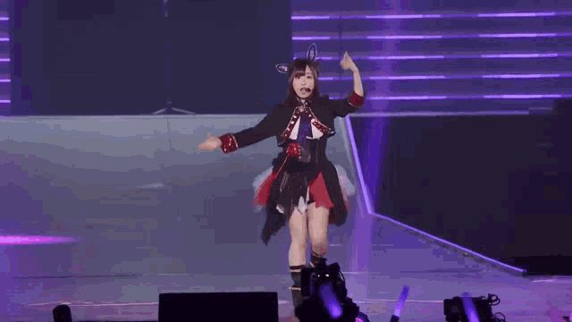a woman is dancing on a stage with her arms outstretched and a microphone in her hand .