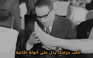 a black and white photo of a man in a suit and tie with arabic writing on the bottom