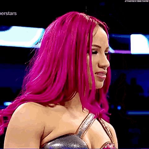 a woman with bright pink hair is wearing a silver top and looking down .