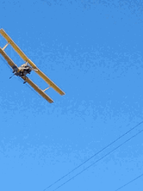a small yellow airplane is flying in the blue sky