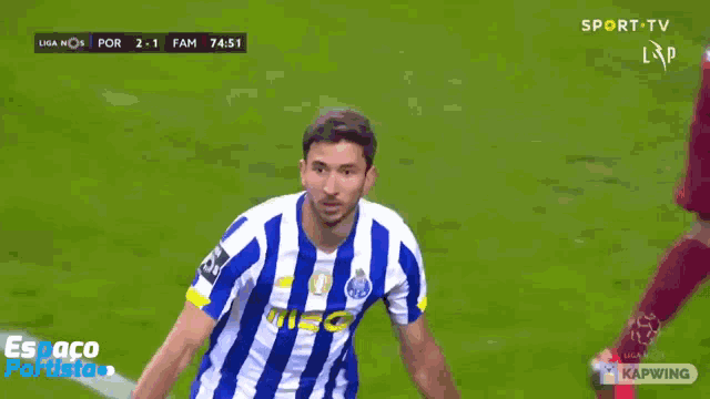 a man in a blue and white striped shirt is pointing up while playing soccer