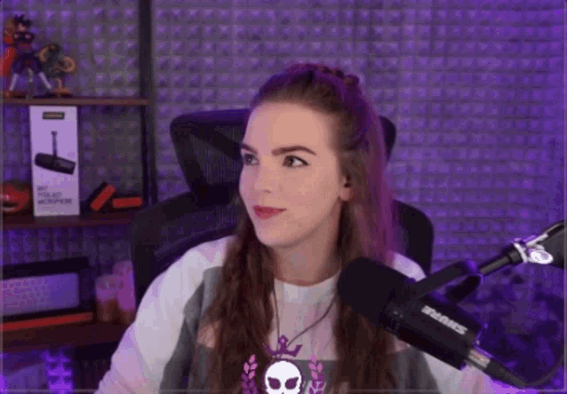a woman sitting in front of a shure microphone in a purple room
