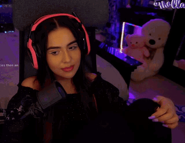 a woman wearing pink headphones is sitting in front of a microphone and a sign that says hello