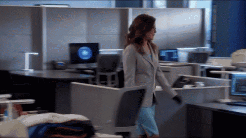 a woman in a blue dress is standing in an office