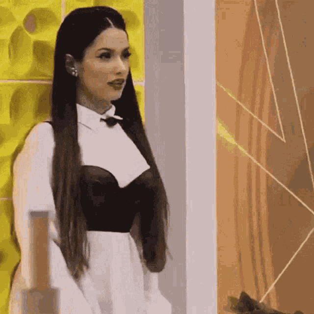 a woman in a white dress and black corset is standing in front of a wall .