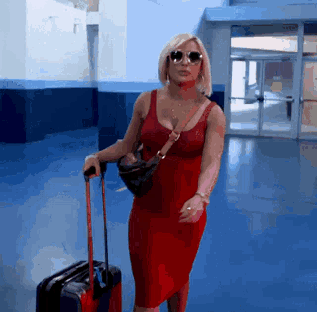 a woman in a red dress pulling a suitcase
