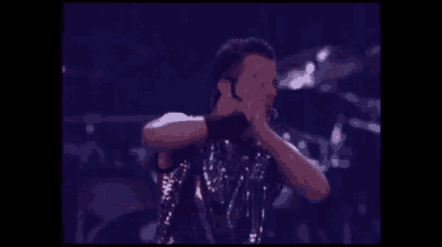 a man in a sequined tank top is holding his hands together
