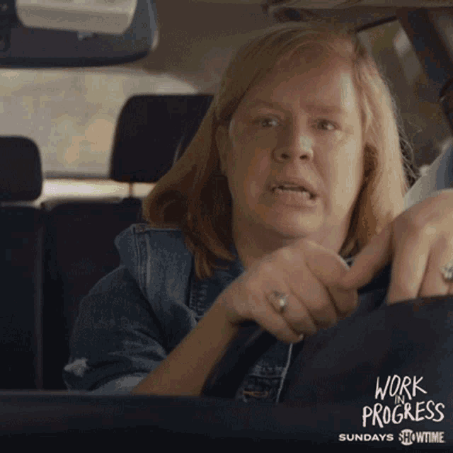 a woman is driving a car with the words work progress sundays showtime behind her