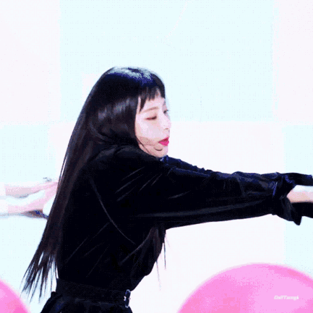 a woman in a black dress is dancing in front of balloons .