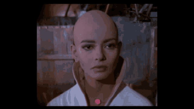 a woman with a shaved head and a pink collar