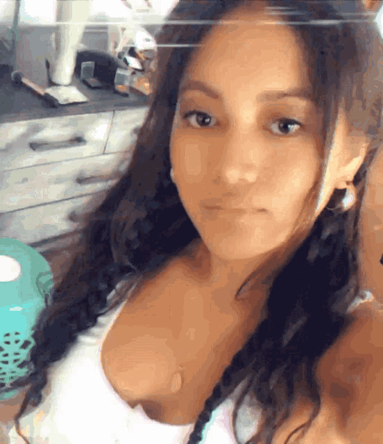 a woman taking a selfie with a white tank top