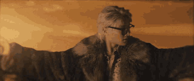 a woman wearing glasses and a fur coat stands with her arms outstretched