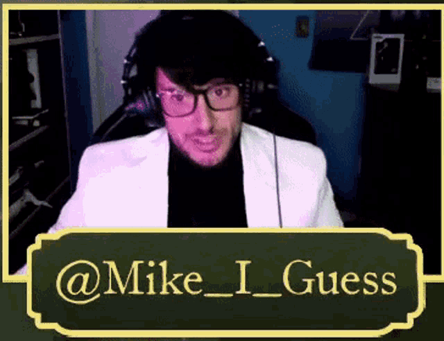 a man wearing glasses and headphones is sitting in front of a chalkboard with the name mike i guess on it