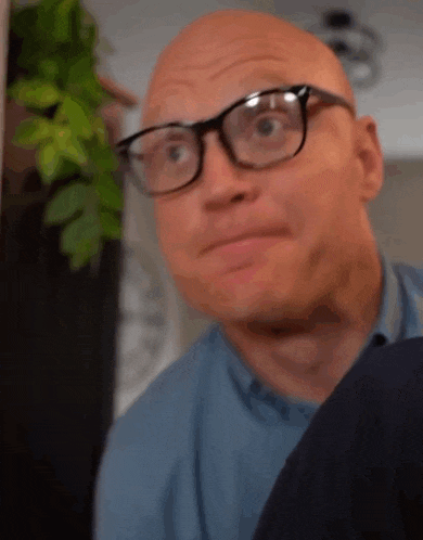 a bald man with glasses is making a funny face .
