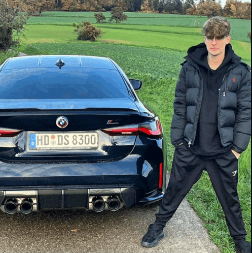 a man is standing in front of a black bmw with a license plate that says hd ds 8300