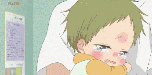 a baby is crying while being held by a person in a hospital bed .