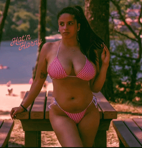 a woman in a bikini is sitting at a picnic table with the words hot n horny written on the bottom