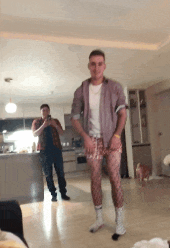 a man wearing fishnet socks stands in a living room