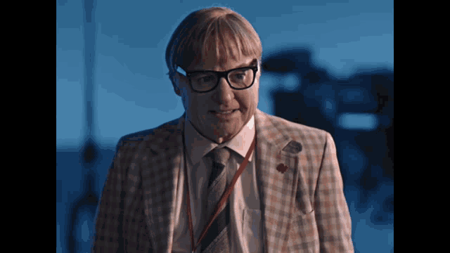 a man with glasses and a lanyard around his neck is smiling