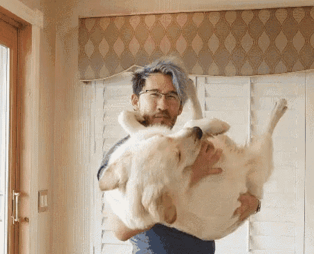 a man with blue hair is holding a large white dog in his arms